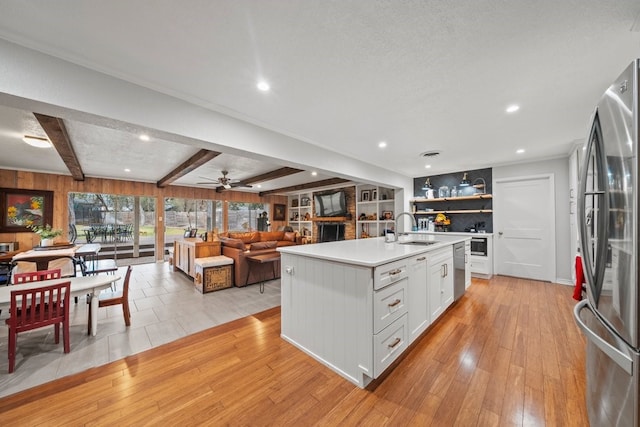 kitchen with sink, appliances with stainless steel finishes, an island with sink, light hardwood / wood-style floors, and white cabinets