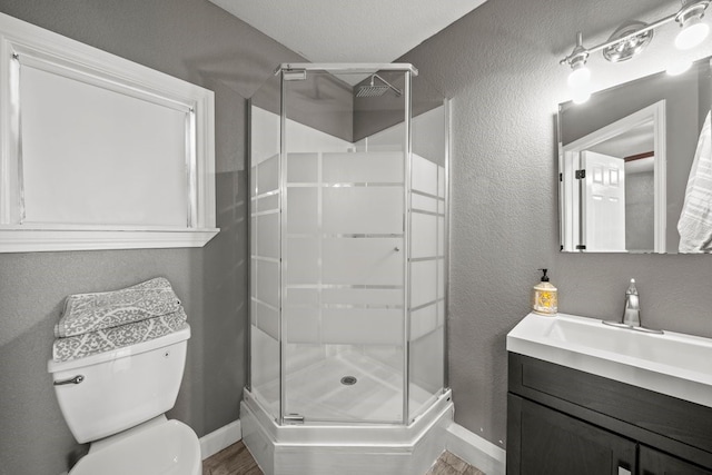 bathroom with vanity, a shower with door, and toilet