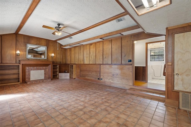 unfurnished living room featuring vaulted ceiling, ceiling fan, and wood walls