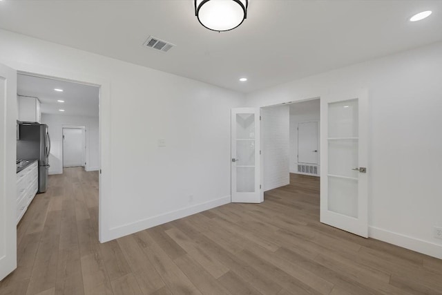 spare room with light hardwood / wood-style flooring and french doors