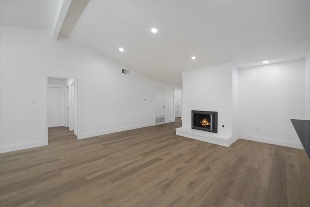 unfurnished living room featuring hardwood / wood-style flooring, a fireplace, and vaulted ceiling with beams