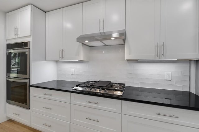 kitchen with light wood-type flooring, white cabinetry, stainless steel appliances, and decorative backsplash