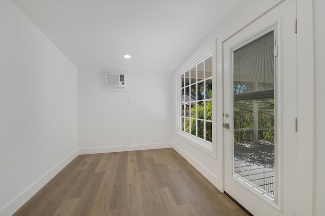 empty room featuring a wall unit AC and light hardwood / wood-style floors