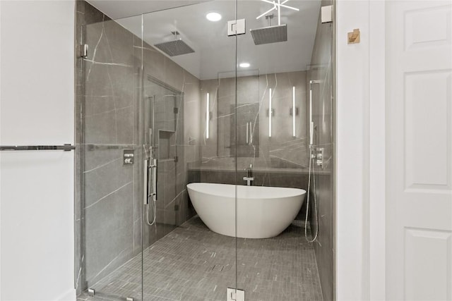 bathroom featuring a soaking tub, a shower stall, tile walls, and recessed lighting