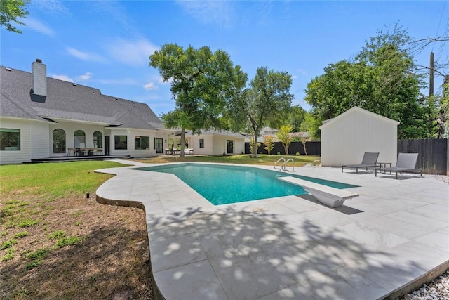 view of pool featuring fence, a diving board, a lawn, a fenced in pool, and a patio area