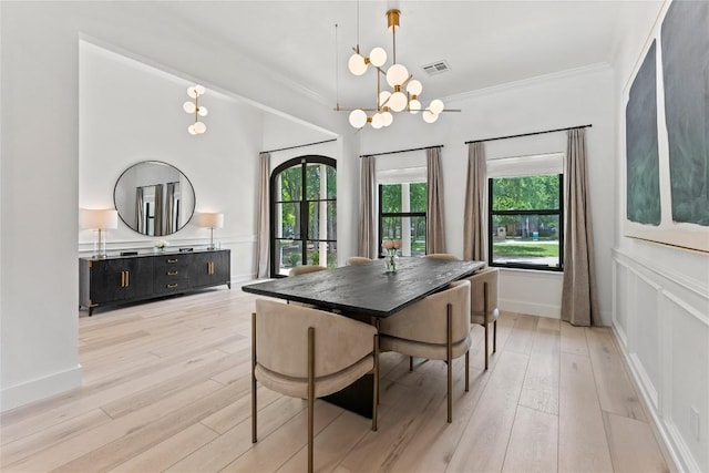 dining room featuring light wood-type flooring, an inviting chandelier, visible vents, and crown molding