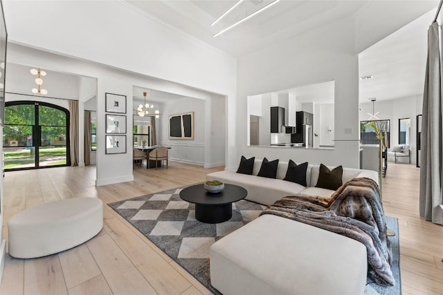 living area featuring light wood-style floors, a high ceiling, and an inviting chandelier