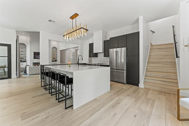 kitchen with arched walkways, high quality fridge, a sink, visible vents, and light countertops