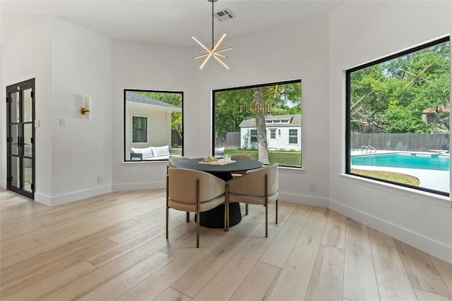 dining space featuring light wood finished floors, a wealth of natural light, and an inviting chandelier