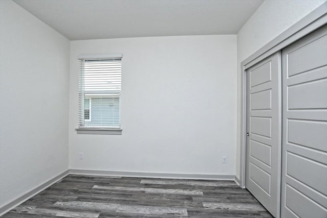 unfurnished bedroom with dark wood-type flooring and a closet