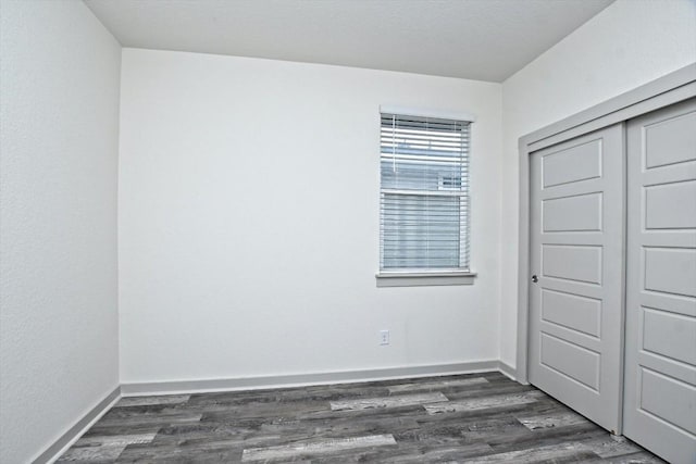 unfurnished bedroom with dark hardwood / wood-style flooring and a closet