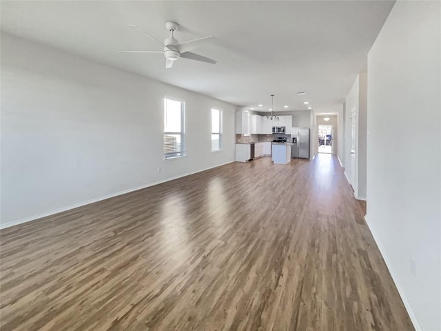 unfurnished living room featuring ceiling fan and dark hardwood / wood-style floors