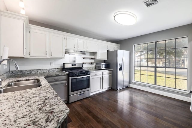 kitchen with dark hardwood / wood-style floors, sink, white cabinets, stainless steel appliances, and light stone countertops