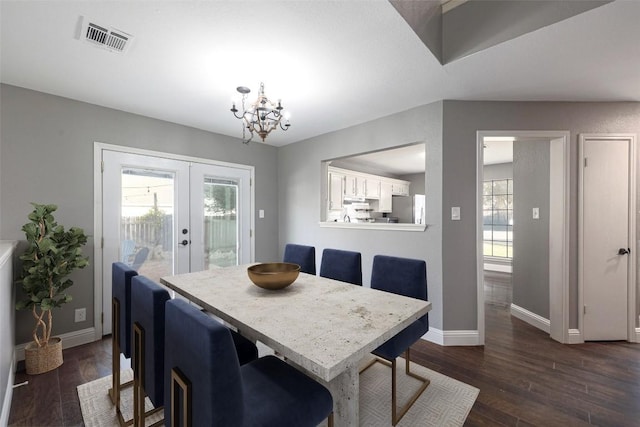 dining area with a healthy amount of sunlight, dark wood-type flooring, an inviting chandelier, and french doors