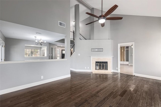 unfurnished living room featuring lofted ceiling with beams, a premium fireplace, dark wood-type flooring, and ceiling fan with notable chandelier