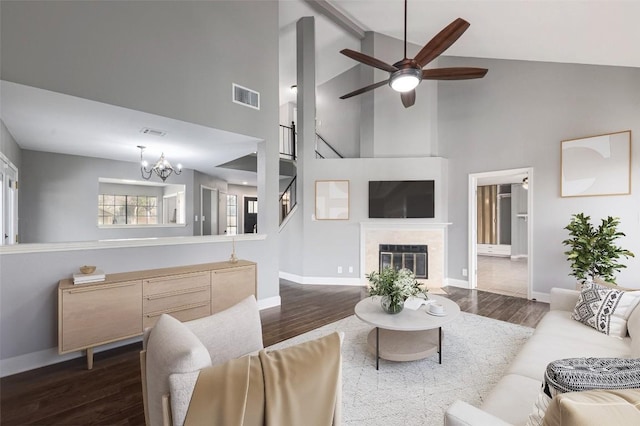 living room with a premium fireplace, dark hardwood / wood-style flooring, and ceiling fan with notable chandelier