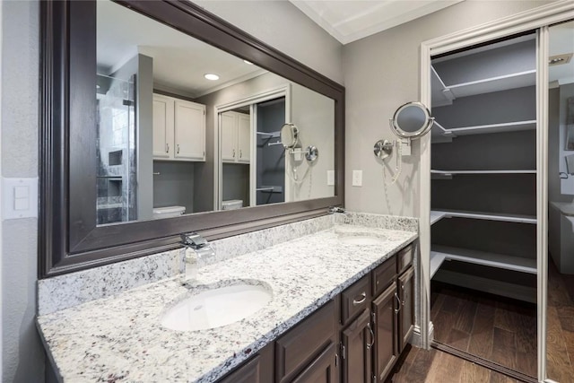 bathroom with hardwood / wood-style flooring, vanity, ornamental molding, and toilet