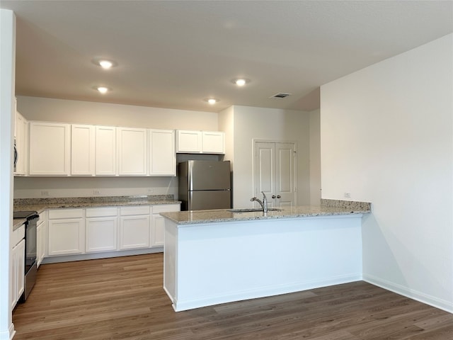 kitchen with sink, appliances with stainless steel finishes, white cabinetry, light stone countertops, and kitchen peninsula