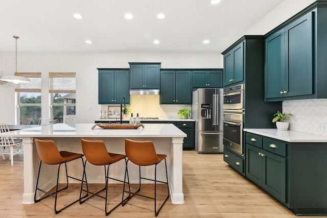 kitchen featuring pendant lighting, stainless steel appliances, a kitchen breakfast bar, and a center island with sink