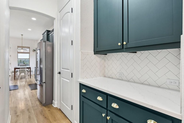 kitchen with decorative light fixtures, tasteful backsplash, light hardwood / wood-style floors, light stone counters, and high end fridge