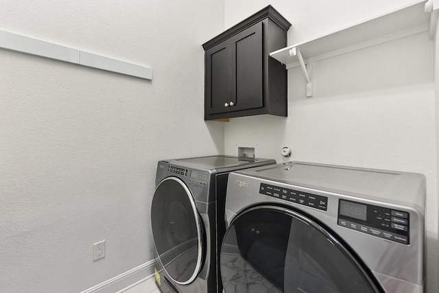 clothes washing area featuring washing machine and dryer and cabinets