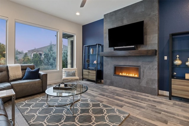 living room featuring ceiling fan, wood-type flooring, and a fireplace