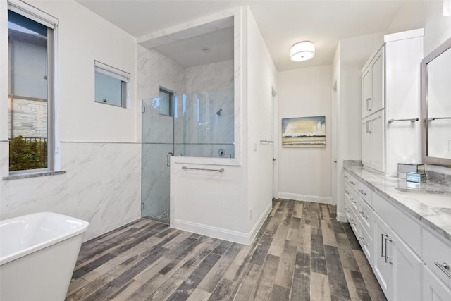 bathroom with vanity, hardwood / wood-style flooring, plus walk in shower, and tile walls