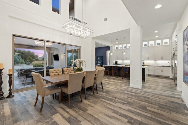 dining area featuring a high ceiling, dark hardwood / wood-style floors, and a notable chandelier