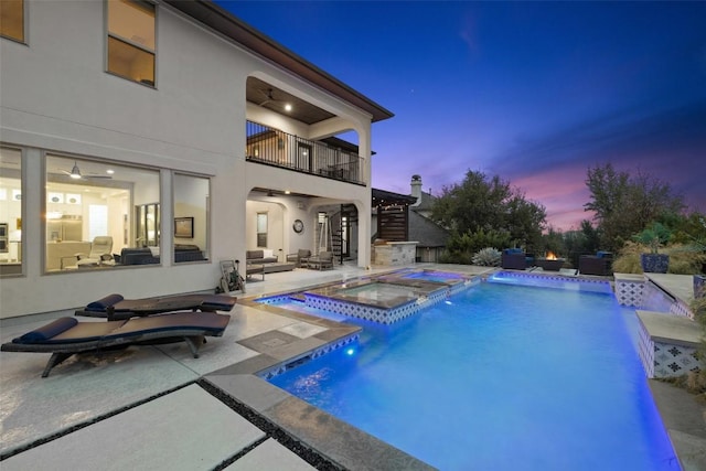 pool at dusk featuring an in ground hot tub and a patio area