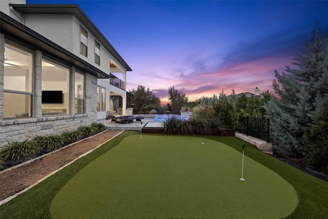 yard at dusk featuring a balcony