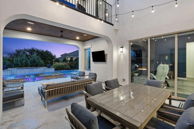 view of patio / terrace with a balcony and a swimming pool with hot tub