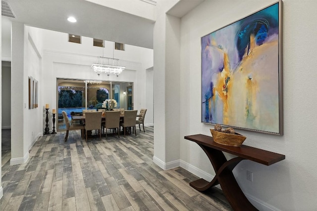 hall featuring wood-type flooring and an inviting chandelier