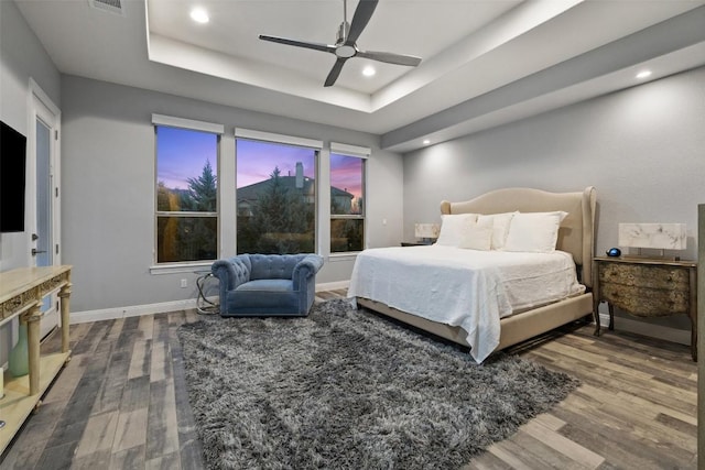 bedroom with a tray ceiling, ceiling fan, and hardwood / wood-style flooring