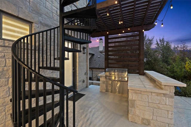 patio terrace at dusk with exterior kitchen and grilling area