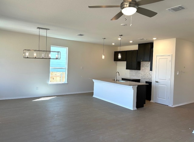 kitchen with wood finished floors, a sink, visible vents, and decorative backsplash