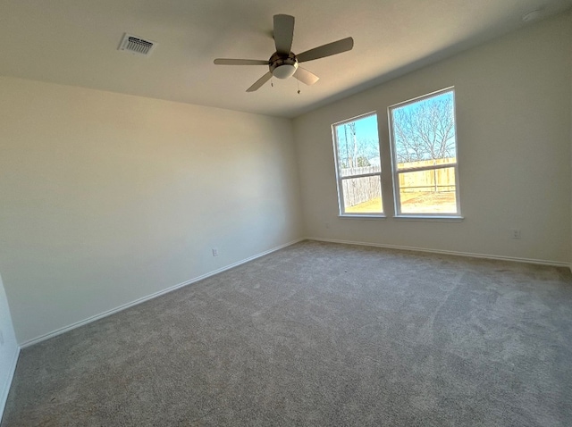 carpeted empty room with a ceiling fan, visible vents, and baseboards