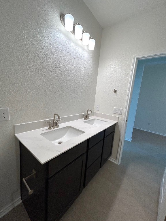 bathroom with double vanity, baseboards, and a sink