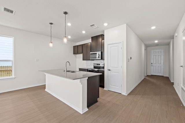 19216 Lady Bird Johnson St, Manor, TX 78653 - kitchen featuring stainless steel appliances, light wood-style flooring, dark brown cabinets, backsplash, and recessed lighting