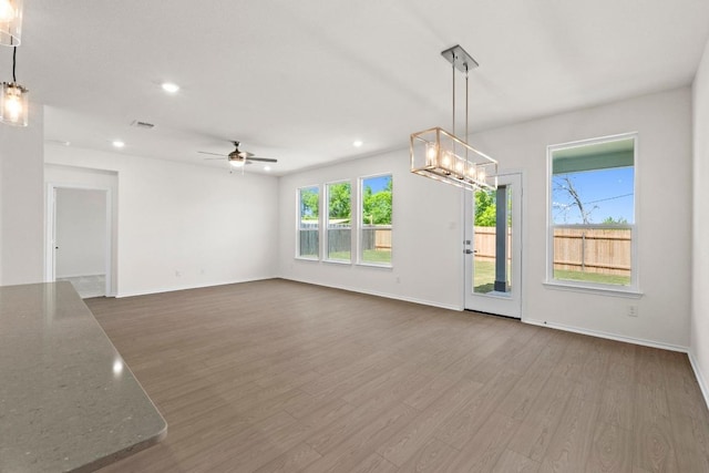 19216 Lady Bird Johnson St, Manor, TX 78653 - unfurnished living room with dark wood-style floors, a ceiling fan, recessed lighting, and a chandelier