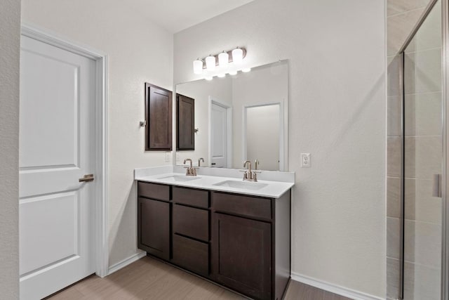 19216 Lady Bird Johnson St, Manor, TX 78653 - bathroom featuring double vanity, wood finished floors, and a tile shower