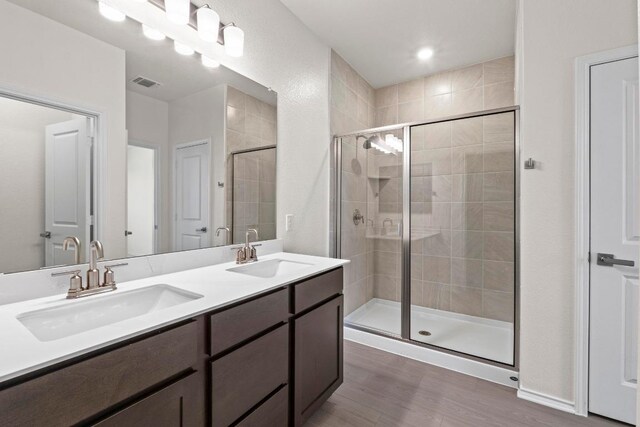 19216 Lady Bird Johnson St, Manor, TX 78653 - bathroom featuring a shower stall, double vanity, and wood finished floors