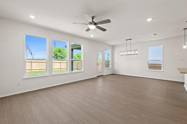 19216 Lady Bird Johnson St, Manor, TX 78653 - unfurnished living room featuring a ceiling fan, dark wood finished floors, recessed lighting, and a chandelier