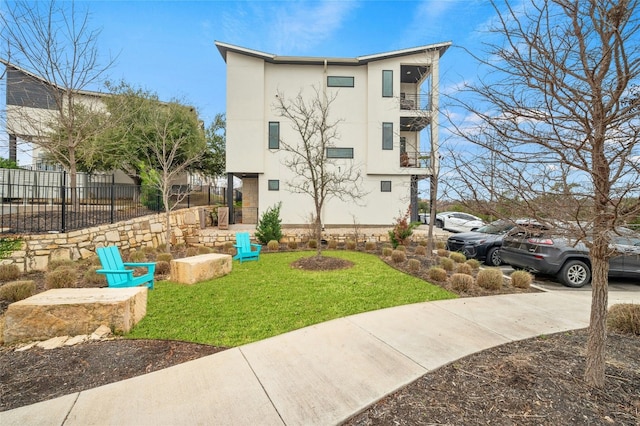 2050 Lohmans Spur Rd Unit 101, Lakeway, TX 78734 - exterior space with fence, stucco siding, a front lawn, and a balcony