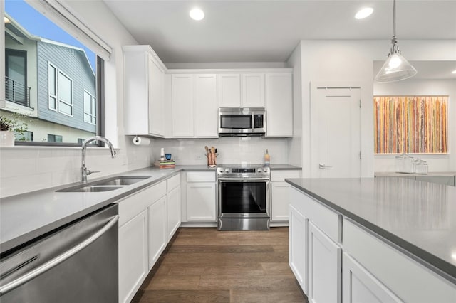 kitchen with sink, white cabinetry, hanging light fixtures, stainless steel appliances, and dark hardwood / wood-style floors