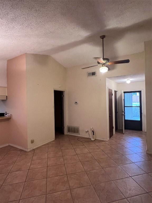 tiled spare room featuring lofted ceiling, a textured ceiling, and ceiling fan