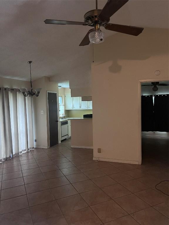 unfurnished living room featuring tile patterned flooring, ceiling fan with notable chandelier, and lofted ceiling