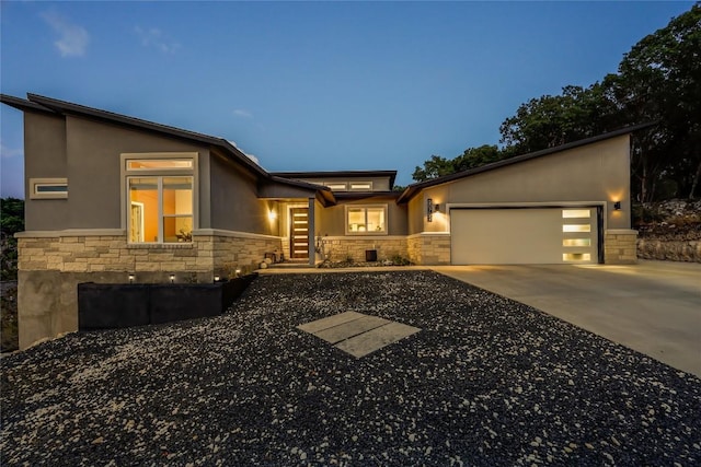 view of front facade with a garage, concrete driveway, stone siding, and stucco siding