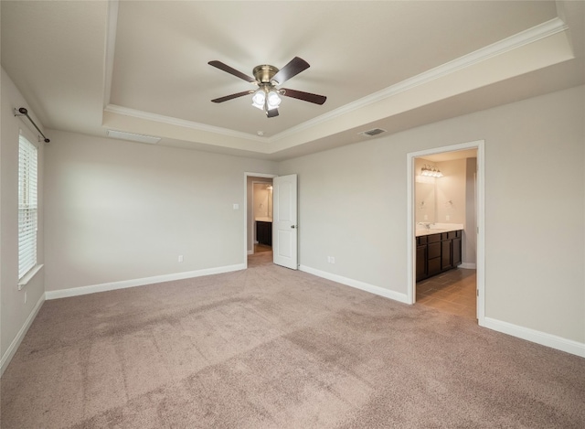 237 Andele Way, Liberty Hill, TX 78642 - unfurnished bedroom featuring a raised ceiling, ornamental molding, light carpet, ensuite bath, and a ceiling fan
