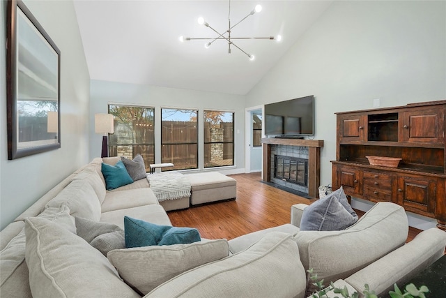 living room with high vaulted ceiling, a fireplace, light wood-type flooring, and a notable chandelier