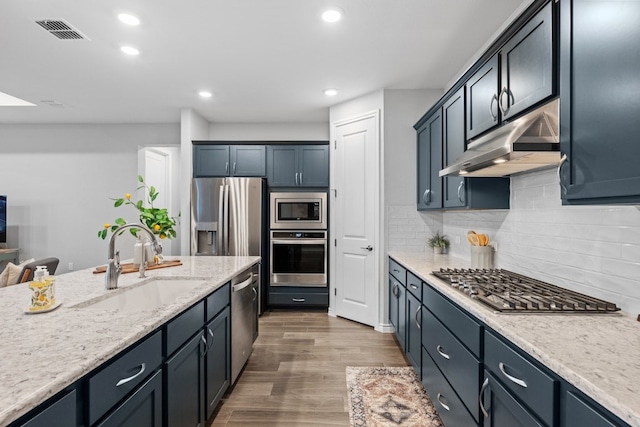 kitchen with visible vents, appliances with stainless steel finishes, a sink, wood finished floors, and under cabinet range hood